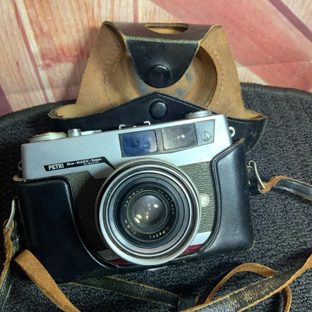 Vintage Petri camera with leather strap and cover.